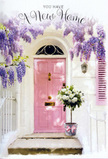The scene shows a peaceful Norbury doorstep transformed into a picture of gentle celebration and welcome, as though caught just moments before the new residents arrive. A softly painted pink front door, with its surface smooth and slightly matte, stands at the heart of the image, bordered by whitewashed walls that bounce light around the entrance and lend the whole façade a calm, airy feel. To one side, a coordinating pastel shutter adds a touch of symmetry and charm, suggesting the kind of lovingly tended home you might find tucked along a quiet residential road off Norbury High Street. Above, generous swathes of wisteria spill down in fragrant lavender and lilac clusters, framing the doorway like an arch made by nature and time. The flowers hang in tapering bunches, each tiny blossom forming a cloud of colour that softens the lines of brick and plaster, while twisted woody stems disappear into the top of the image. Sunlight filters through the foliage in dappled patches, creating soft, shifting shadows reminiscent of a warm afternoon stroll through local streets towards Norbury Station. Resting neatly at the threshold is a simple grey metal bucket, transformed into a stylish vessel by an abundant arrangement of creamy white roses. Their petals are plush and layered, some buds just beginning to unfurl, all accented with small sprays of soft green leaves that give the bouquet depth and texture. A delicate pink ribbon is tied around the base, its bow relaxed but precise, echoing the door's colour and bringing the composition into pastel harmony. The entire doorway feels like a quiet, fragrant blessing for someone settling into a new home in Norbury, capturing the hope, tenderness, and promise that flowers can bring to a fresh start.